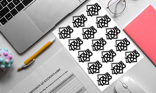 Stanowisko pracy z laptopem, długopisem, notesem i arkuszem naklejek 