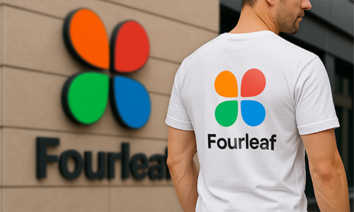 Hombre usando camiseta blanca personalizada con el colorido logo “Fourleaf” que coincide con el logotipo en la pared del edificio en el fondo.