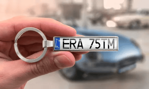 Silverfärgad nyckelring med registreringsskylt visar personliga nummer när den hålls i handen