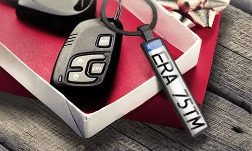 Nyckelring i metall med registreringsskylt visar graverade nummer bredvid bilnycklarna