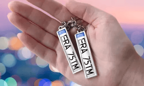 Breloki z niestandardową tablicą rejestracyjną i spersonalizowanymi numerami, trzymane w ręce