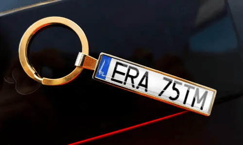 Nummernschild-Schlüsselanhänger an Schlüsseln in der Tasche, mit Auto im Hintergrund