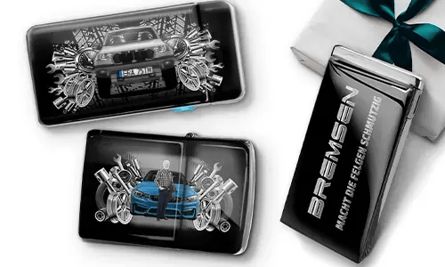 Three automotive-themed items featuring car illustrations and machinery motifs, arranged with a gift box tied with a green ribbon on the side.