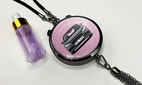 Pendant with pink background and white sports car, next to purple dropper bottle with gold cap