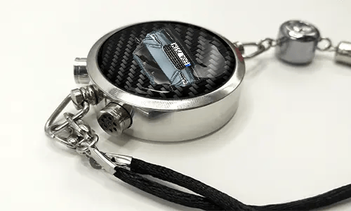 Round car key fob with carbon fiber face, buttons labeled LOCK and UNLOCK, braided black cord attached