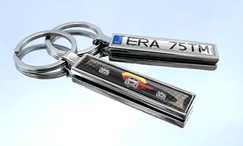 Comic-style license plate keychains with colorful car graphics displayed on a reflective surface