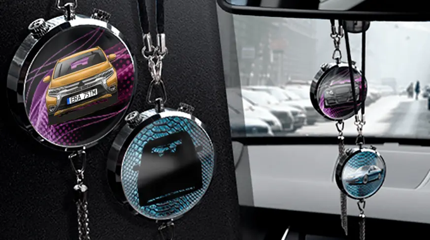Two circular car air fresheners hanging from rearview mirror: left with black car, right with blue car